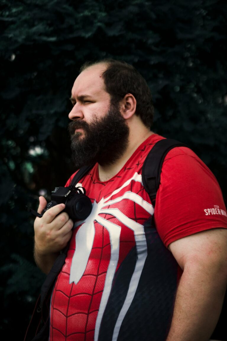 Man in Spider-Man costume holding a camera outdoors, blending cosplay and photography.